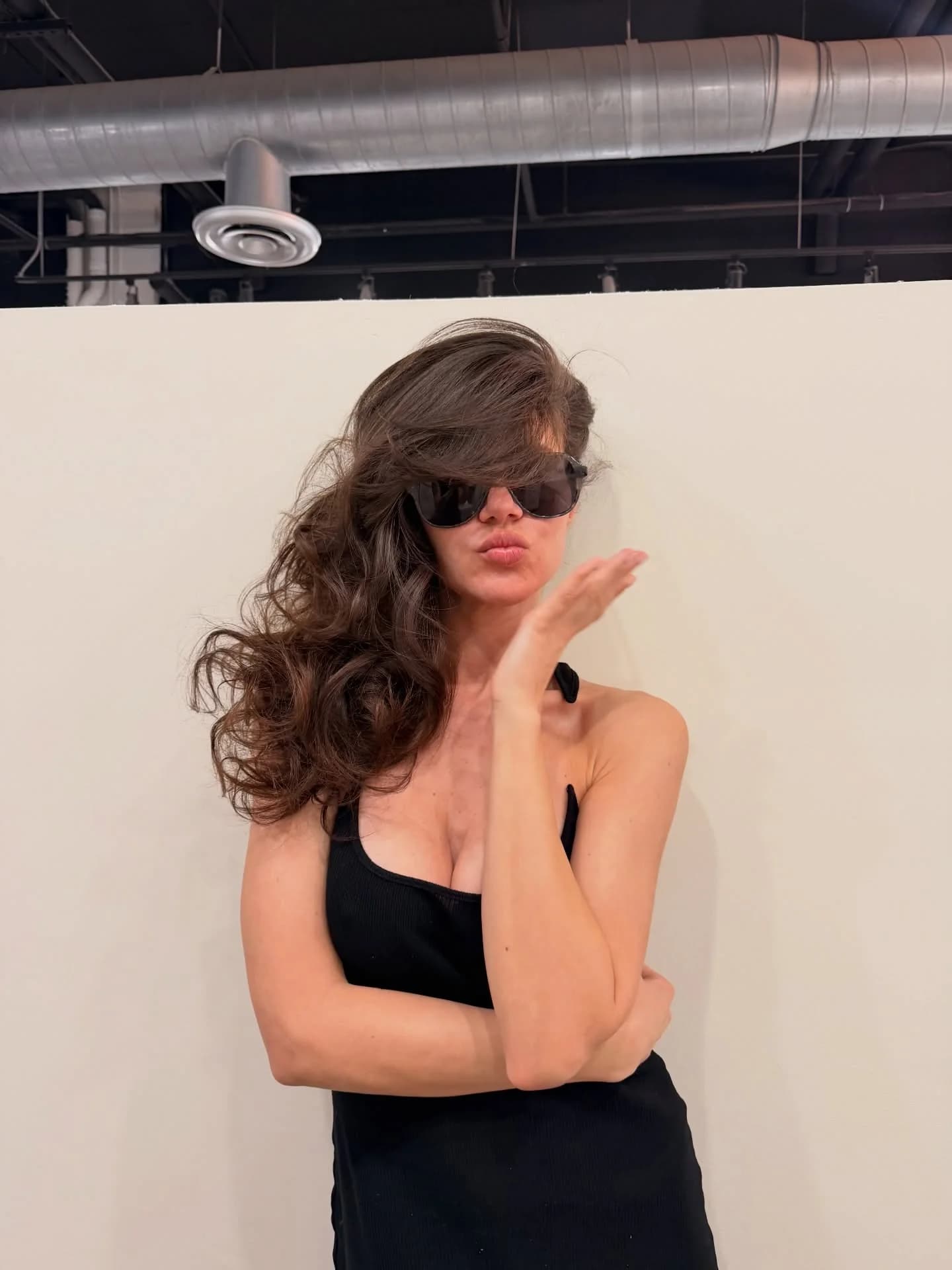 Woman in sunglasses with voluminous brunette curls over one shoulder