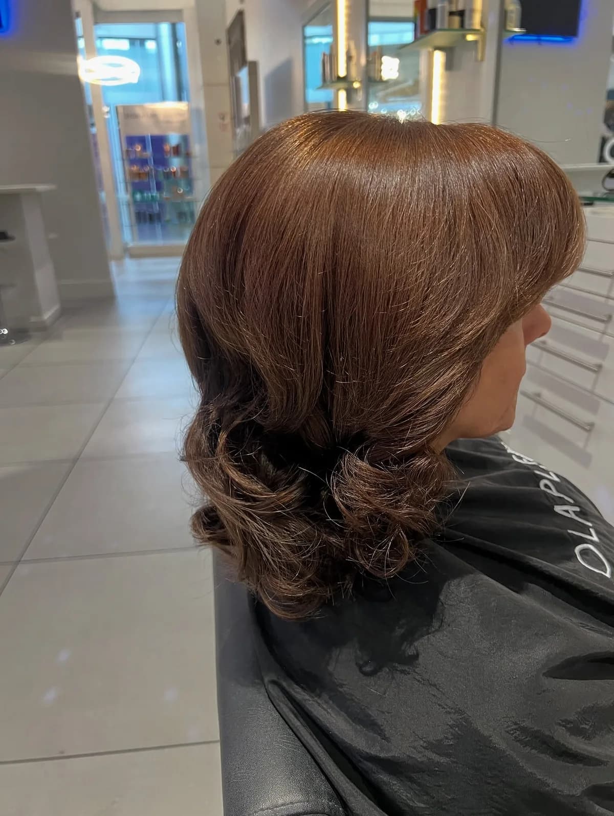 Glossy chestnut hair styled with soft curls, photographed from the side