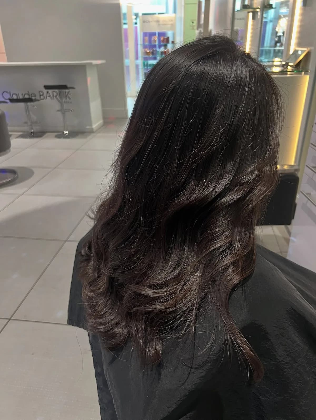 Long glossy dark hair styled in soft waves, photographed from the side