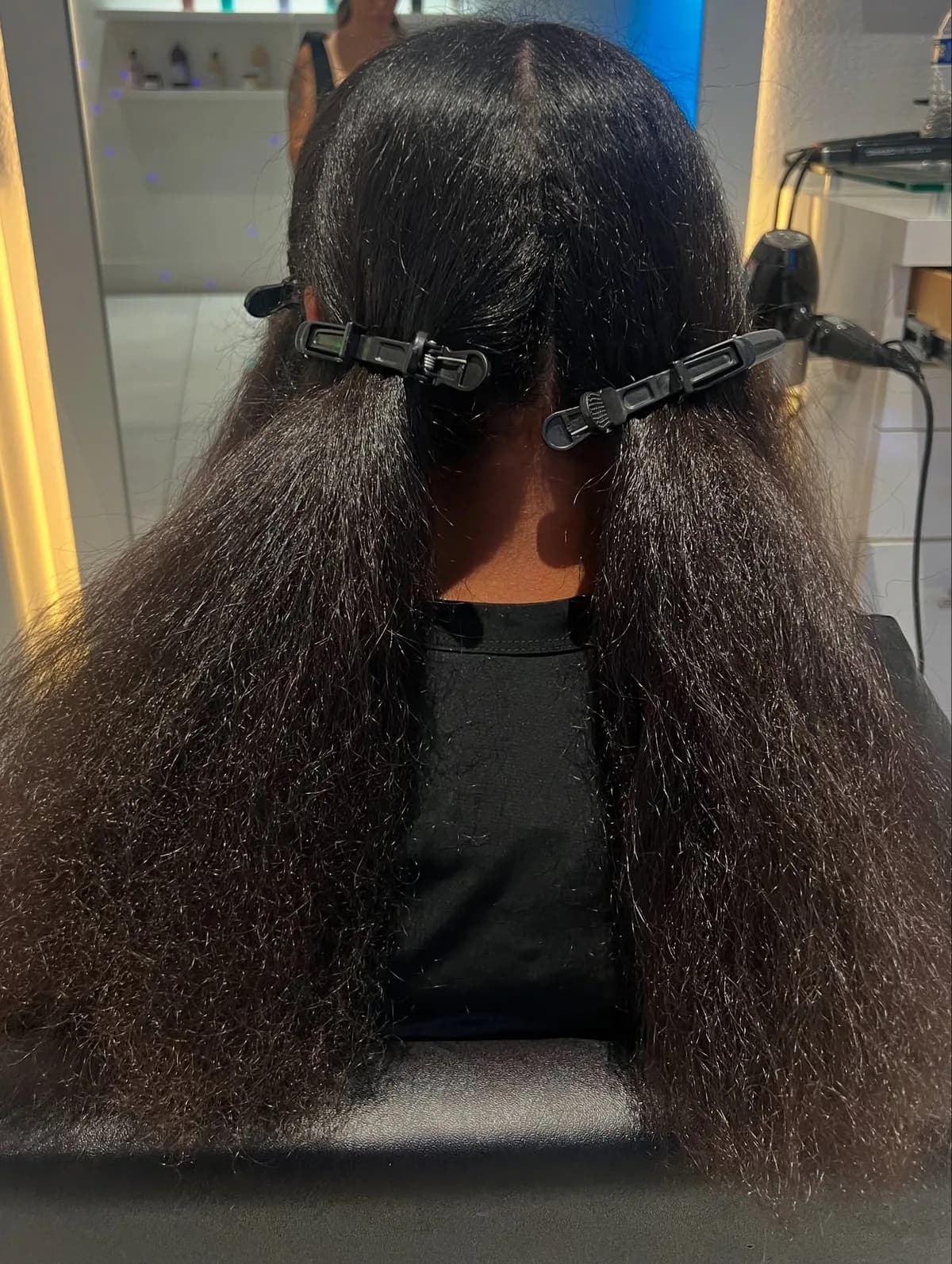 Naturally textured dark hair divided into sections with salon clips