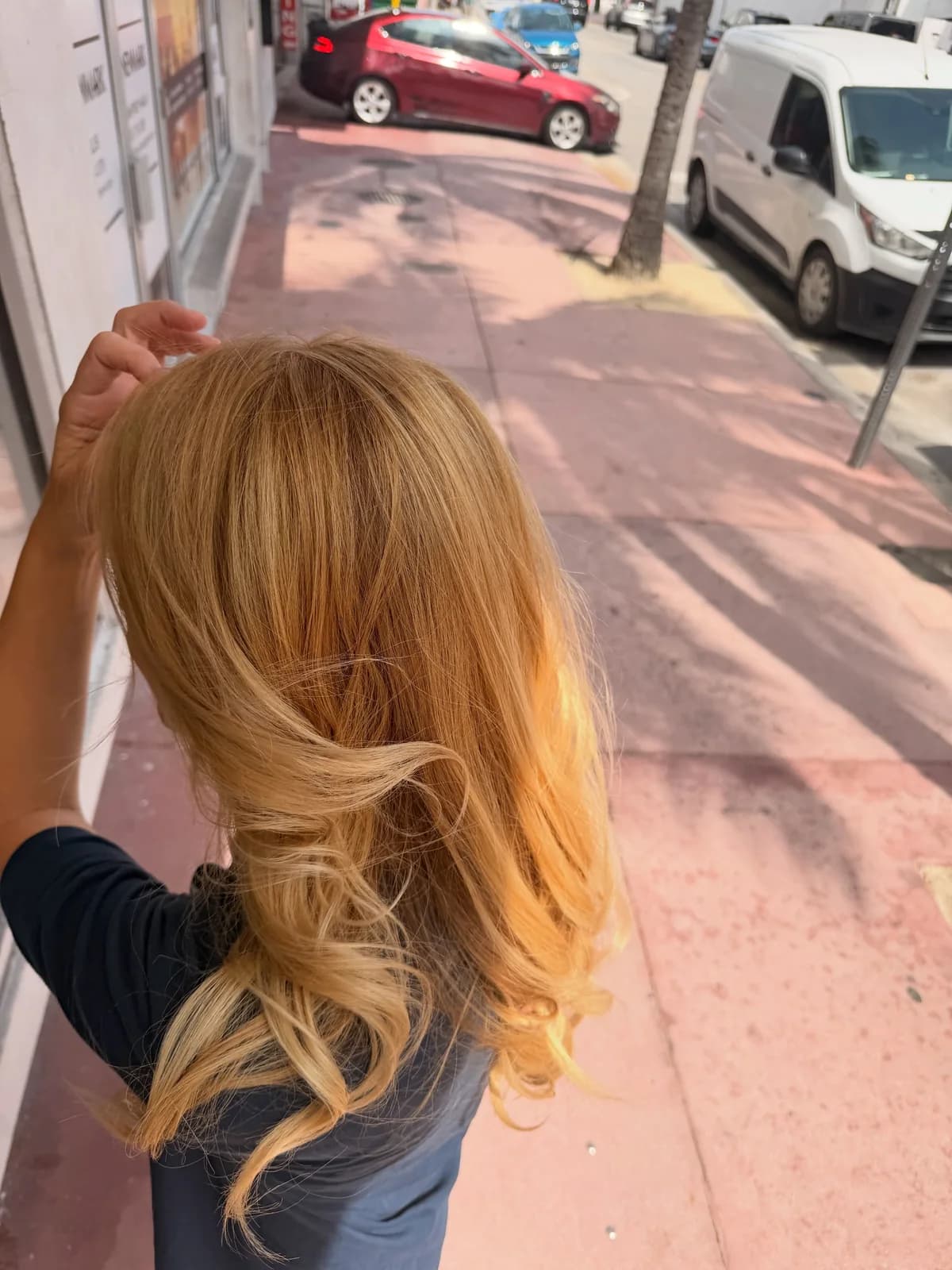Close view of golden blonde hair at the crown and curled lengths outdoors